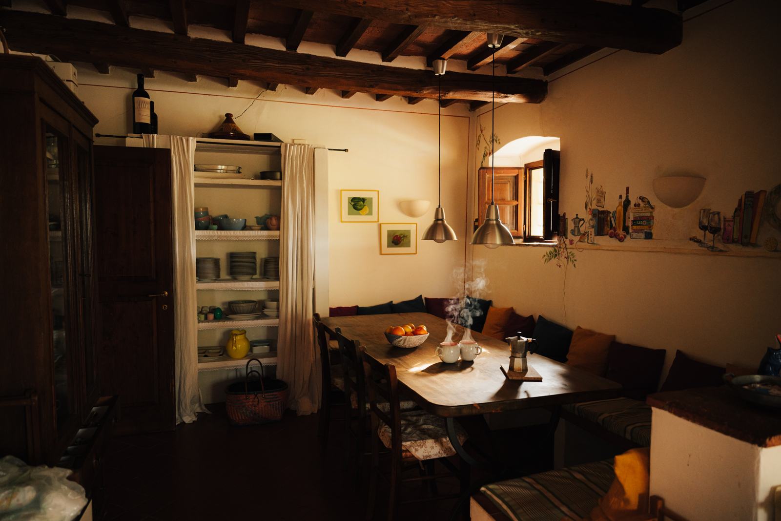 Cucina con panca d'angolo, lungo tavolo in legno e parete dipinta a mano